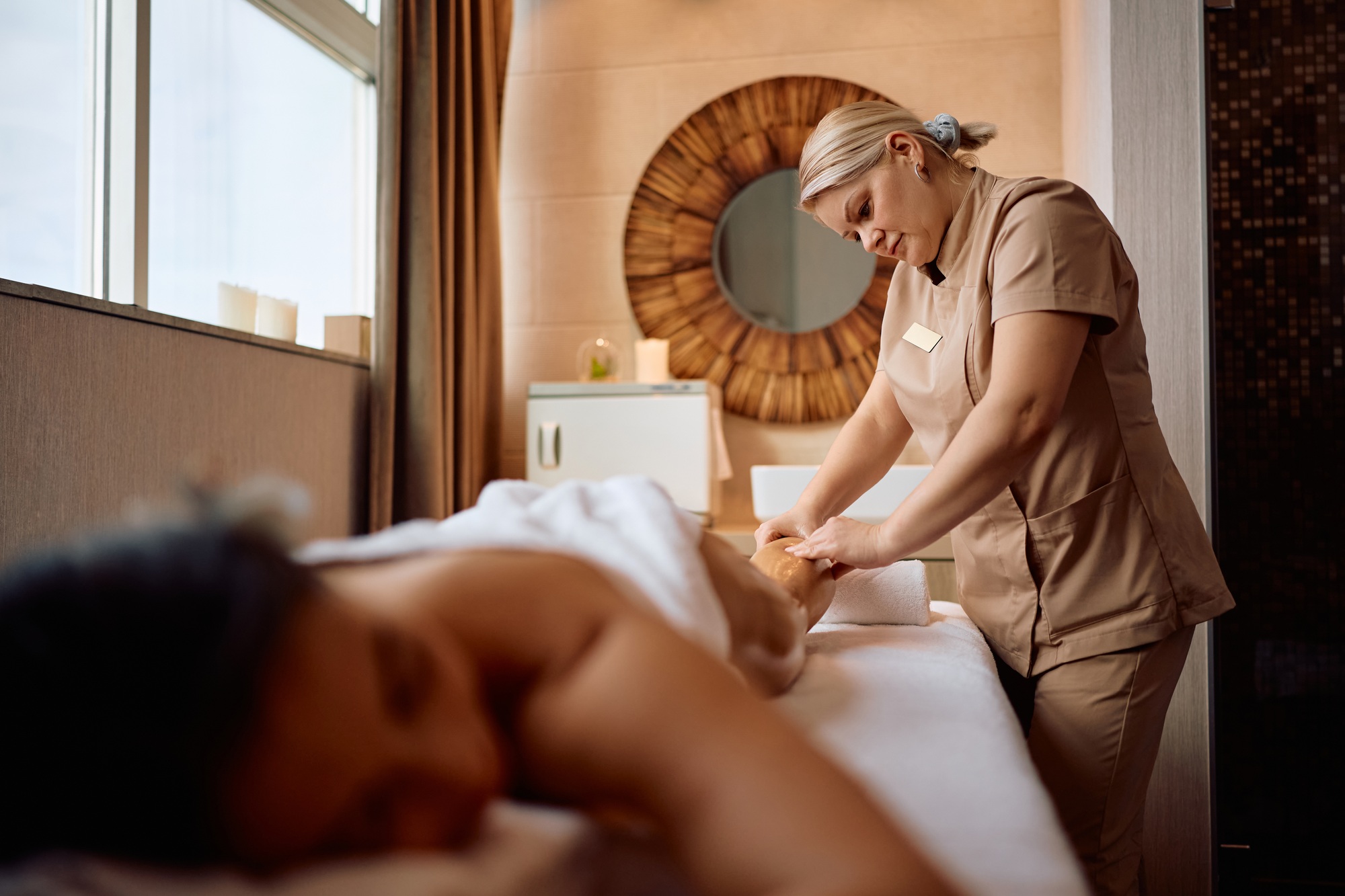 Spa masseuse massaging leg of a woman during a relaxing treatment.